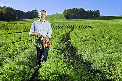 Biopionier Christian Stadler von MORGENTAU Biogemüse GmbH steht in einem Feld mit Karotten in der Hand